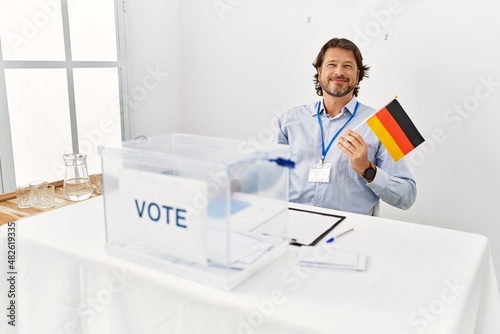 Middle age caucasian man smiling confident holding germany flag working at electoral college