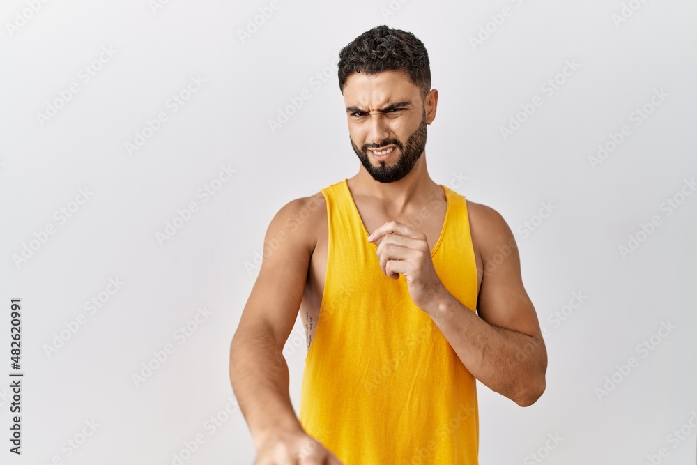 Young handsome man with beard standing over isolated background disgusted expression, displeased and fearful doing disgust face because aversion reaction. with hands raised