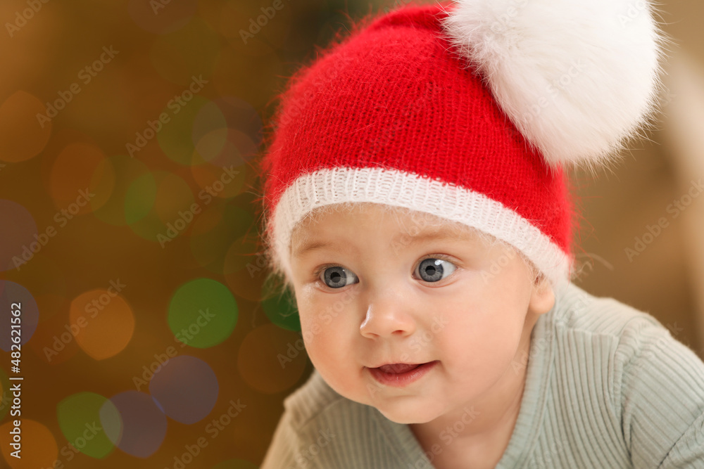 Cute little baby and blurred Christmas lights on background, space for text. Winter holiday Cute little baby and blurred Christmas lights on background, space for text. Winter holiday