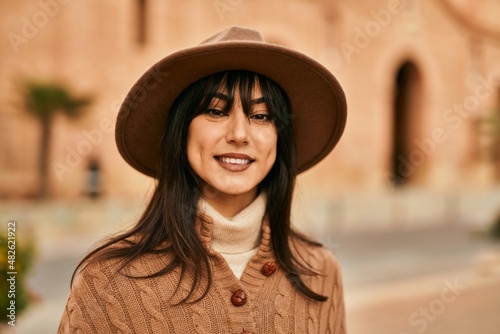 Brunette woman wearing winter hat smiling outdoors at the city © Krakenimages.com