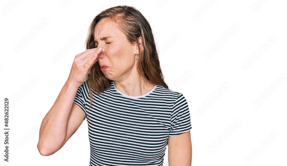 Young blonde woman wearing casual clothes smelling something stinky and disgusting, intolerable smell, holding breath with fingers on nose. bad smell Young blonde woman wearing casual clothes smelling something stinky and disgusting, intolerable smell, holding breath with fingers on nose. bad smell