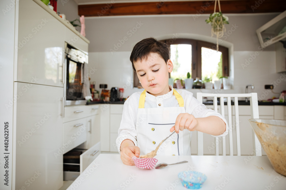 Child in chef costume bakes something. child in the kitchen at home. Experiments in the kitchen. Child plays with dough Child in chef costume bakes something. child in the kitchen at home. Experiments in the kitchen. Child plays with dough