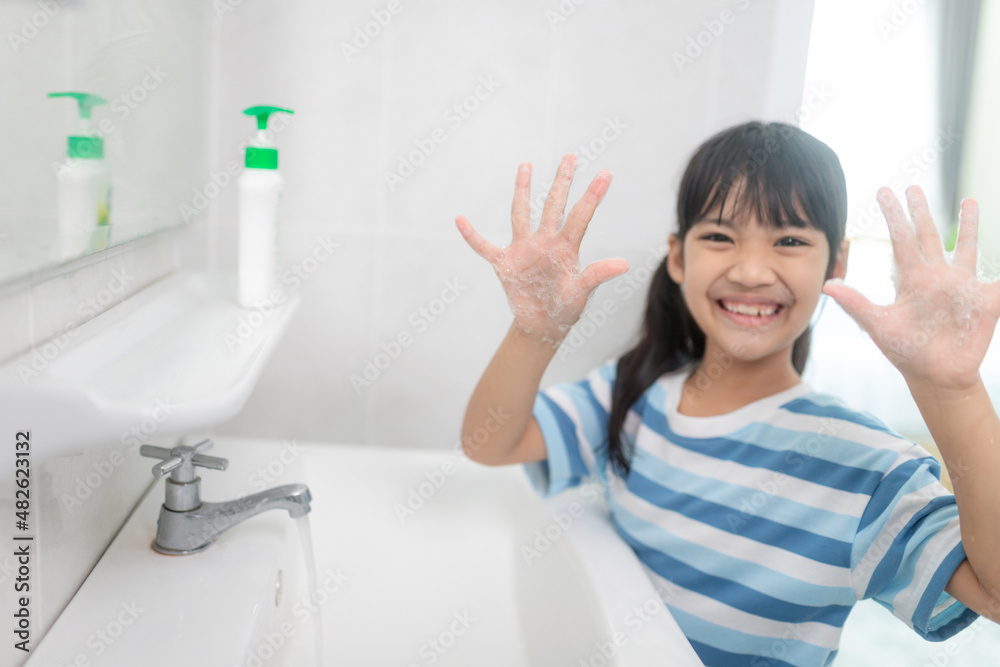 Little Asian girls wash their hands in the bathroom. Soft focus. Copy space.