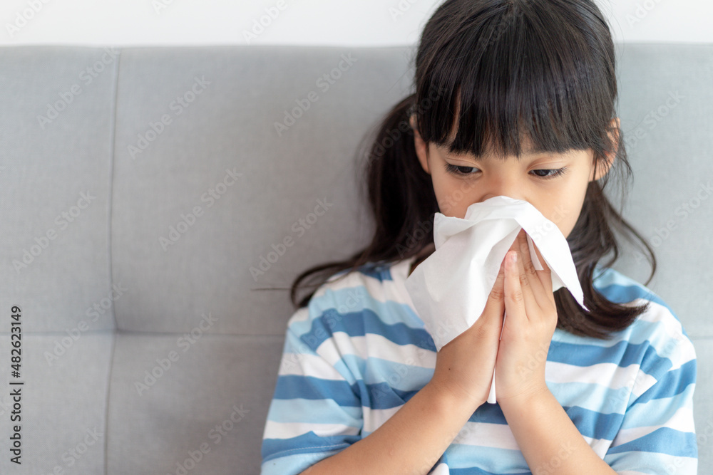 Unhealthy kid blowing nose into tissue, Child suffering from running nose or sneezing, A girl catches a cold when season change, childhood wiping nose with tissue Unhealthy kid blowing nose into tissue, Child suffering from running nose or sneezing, A girl catches a cold when season change, childhood wiping nose with tissue