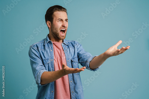 Φωτογραφία Young furious man wearing shirt gesturing and screaming at camera