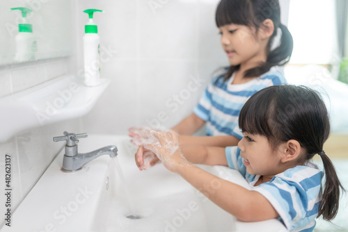 Little Asian girls wash their hands in the bathroom. Soft focus. Copy space.