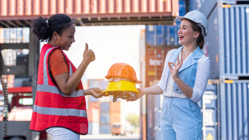 African american woman get safety helmet from Woman CEO cargo container warehouse on activity safety day, assign taske to foreman photo