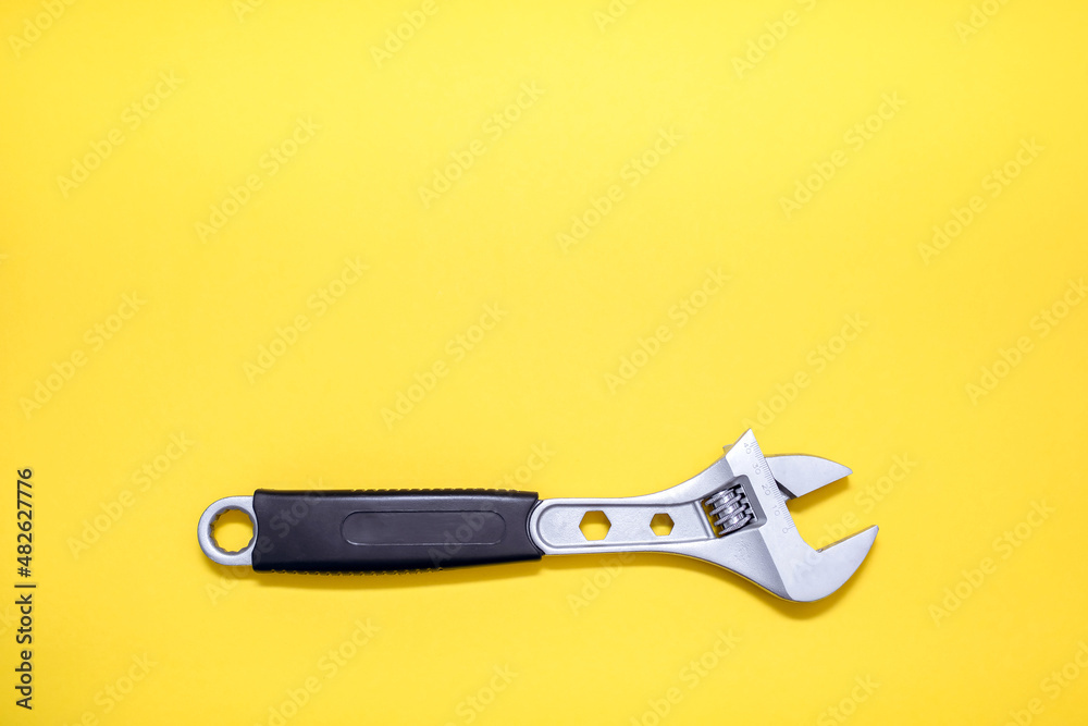 Obraz premium Modern adjustable wrench on a yellow background. The concept of a tool for repair or construction. Special tool for repairing pipes and clamp nuts. Free space for text