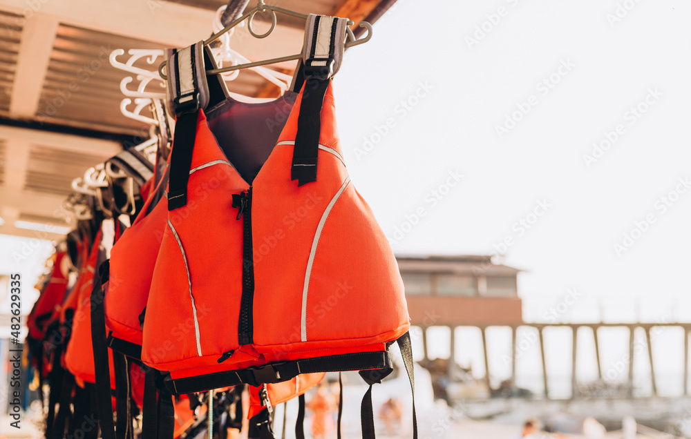 Life jacket on rail for costumer, Red Life jacket with black belts,  Personal flotation device. Life jacket ready to be used by tourist going on  a boat trip. Stock Photo | Adobe