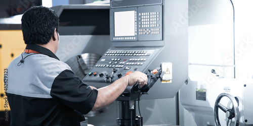 Mechanical technician operate CNC lathe machine in workshop. Industrial manufacturing.
