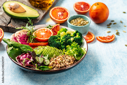 Vegan, detox Buddha bowl with vegetables, avocado, blood orange, broccoli, watermelon radish, spinach, quinoa, pumpkin seeds. Balanced food. Delicious detox diet. Top view
