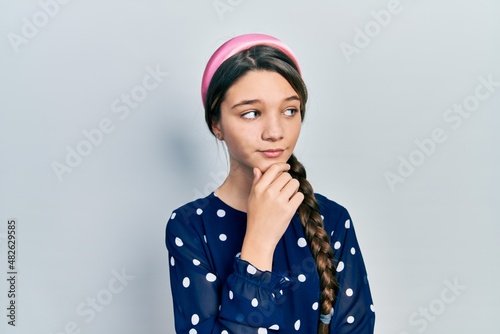 Young brunette girl wearing elegant look with hand on chin thinking about question, pensive expression. smiling with thoughtful face. doubt concept.