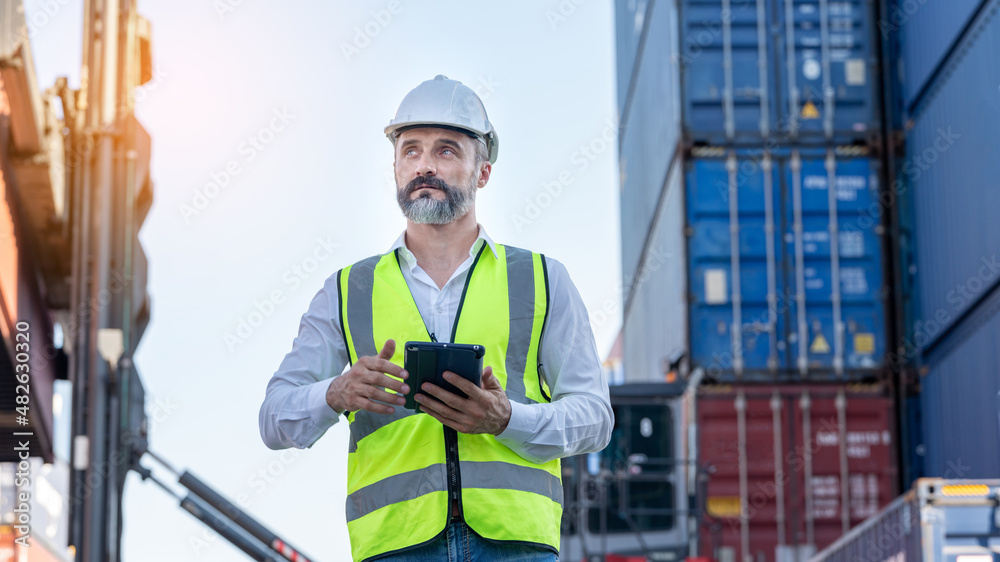 CEO or Manager in white helmet with tablet control loading Containers