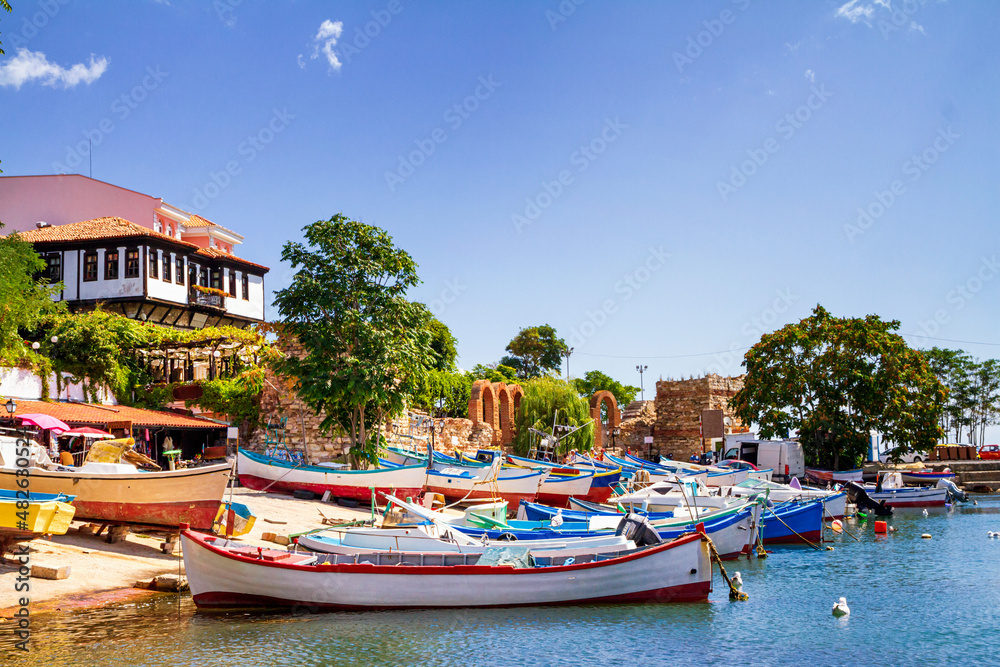 Seaside cityscape - view of the pier with boats and embankment in the Old Town of Nessebar, on the Black Sea coast of Bulgaria
