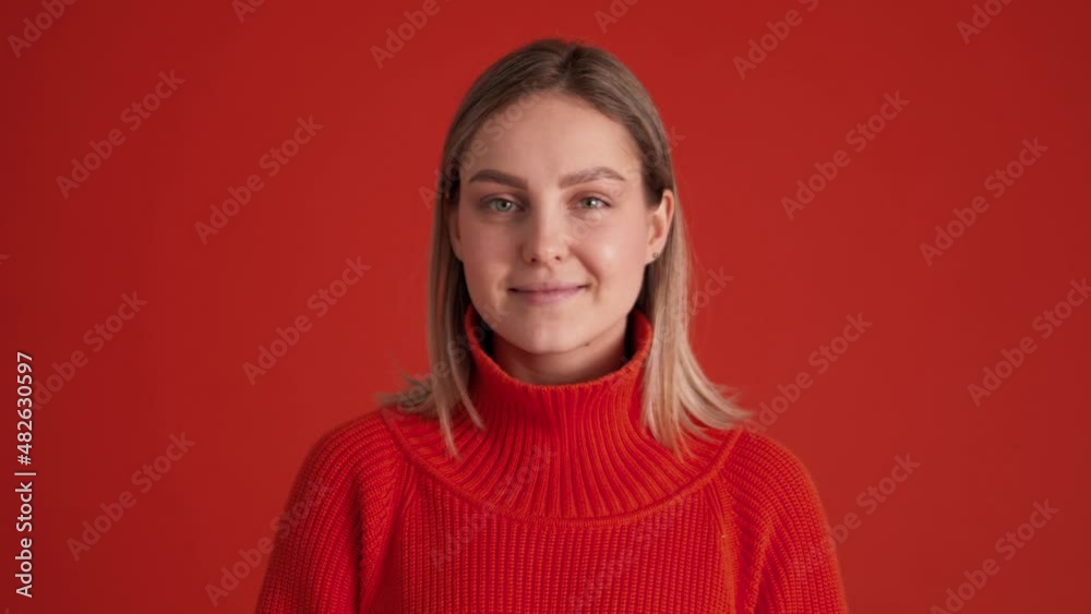 Cheerful woman wearing red sweater looking at the camera in red studio Cheerful woman wearing red sweater looking at the camera in red studio