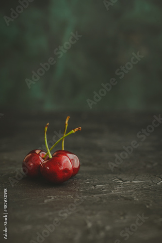 Three cherries on dark background. Close-up.