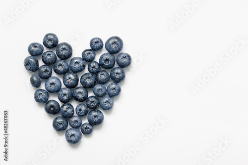 Delicious blueberries formed into a heart shape on white background.
