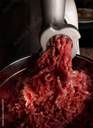 Process of preparing forcemeat by means of a meat grinder. Fresh red mincing close-up on black background with copy space. Selective focus
