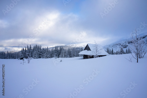 An old hut in a winter landscape with peaks in the background. Gasienicowa Valley. Tatra Mountains.