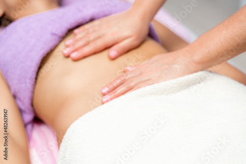 Top view of hands massaging female abdomen.Therapist applying pressure on belly. Woman receiving massage at spa salon © svetograph
