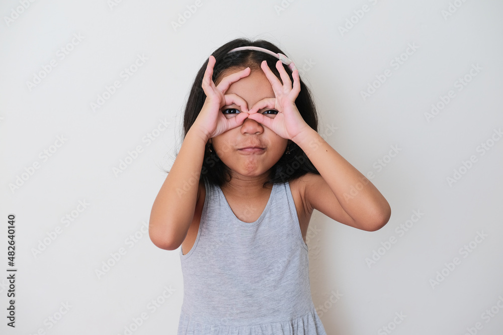 Asian kid showing funny expression when looking to the camera Asian kid showing funny expression when looking to the camera