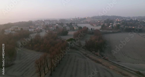 Train passing a rail crossing in Pomelasca countryside on an early winter morning, aerial shot.