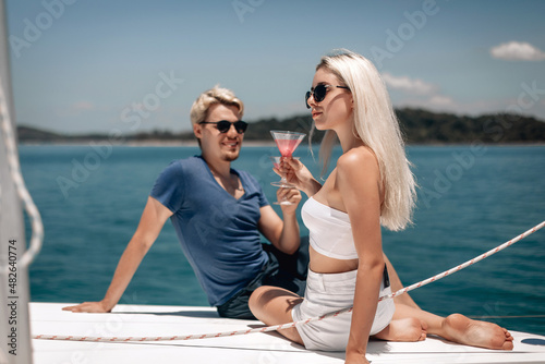 Beautiful adult and pretty lovely models with blond hair having fun outdoors, holding cocktails in crystal glasses. Vacation concept © Semachkovsky 