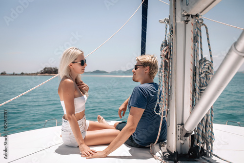 Interesting fascinated blonde couple, a man and a woman sitting and discussing something, taken away by conversation, posing on a white expensive yacht  © Semachkovsky 