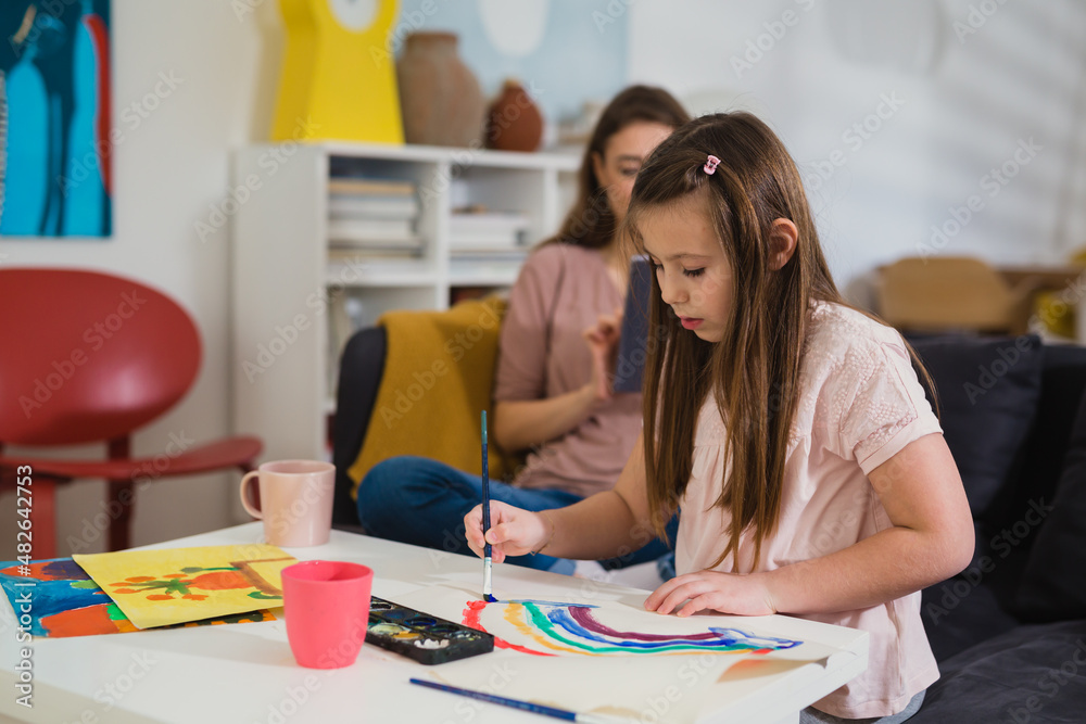 mother and daughter at home. girl drawing picture for her mom mother and daughter at home. girl drawing picture for her mom