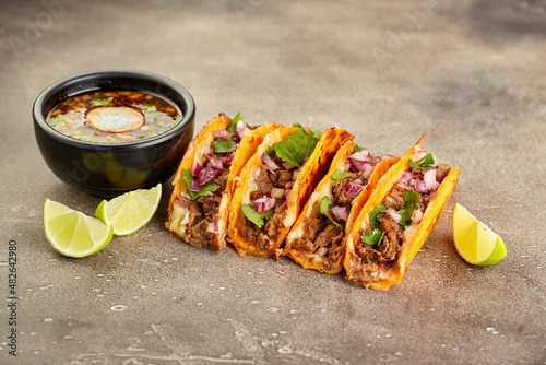 Traditional mexican birria consome soup and four taco with stewed beef photo