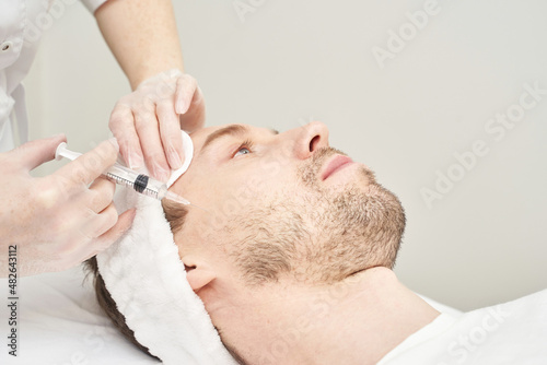 Injection at spa salon. Doctor hands in gloves. Closeup. Pretty male patient. Beauty treatment. Healthy skin procedure. Young man face. Plasmolifting rejuvenation