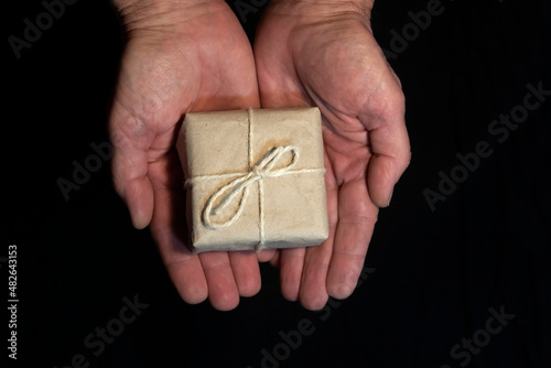 Small box with a gift in hands on a black background.