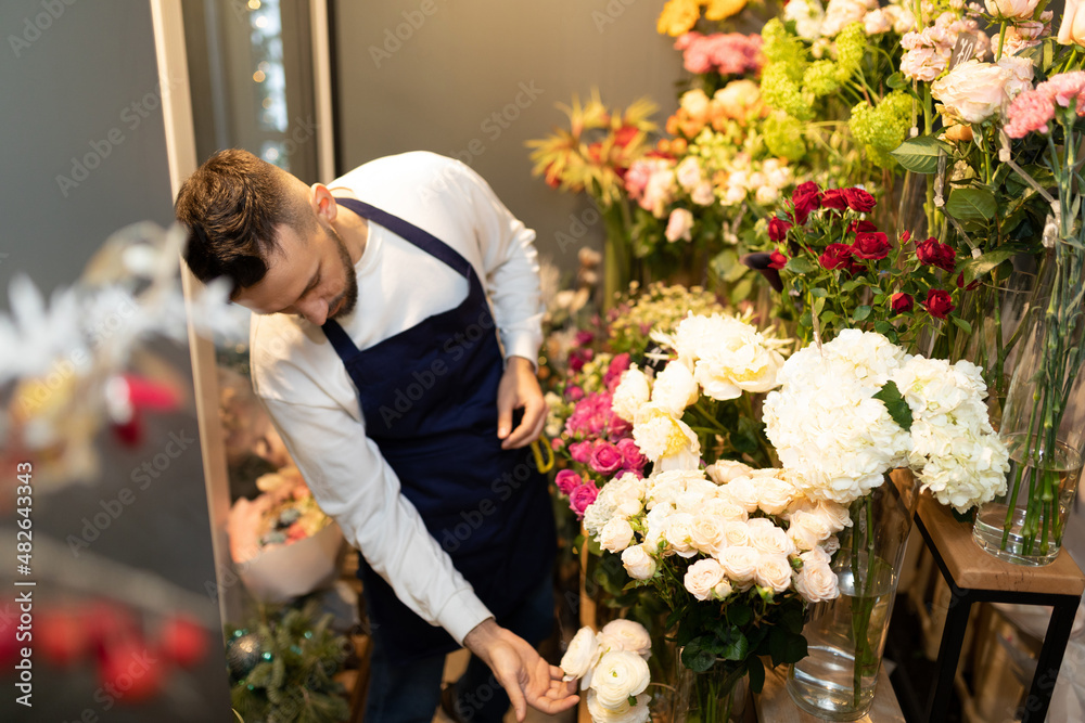 the florist in the refrigerator chooses fresh flowers for a bouquet
