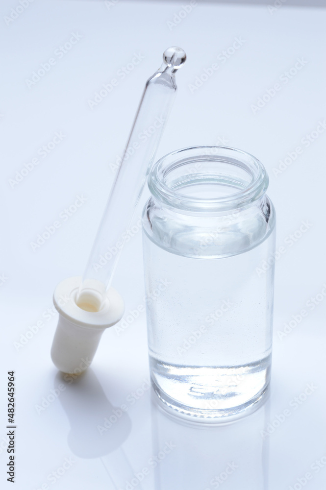 glass transparent jar and a cosmetic pipette with liquid droplets on a white background. glass transparent jar and a cosmetic pipette with liquid droplets on a white background.