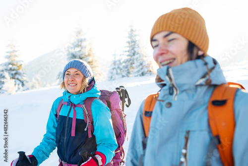 Two women with backpacks walk in the winter trekking