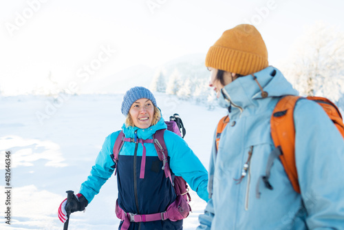 Two women with backpacks walk in the winter trekking