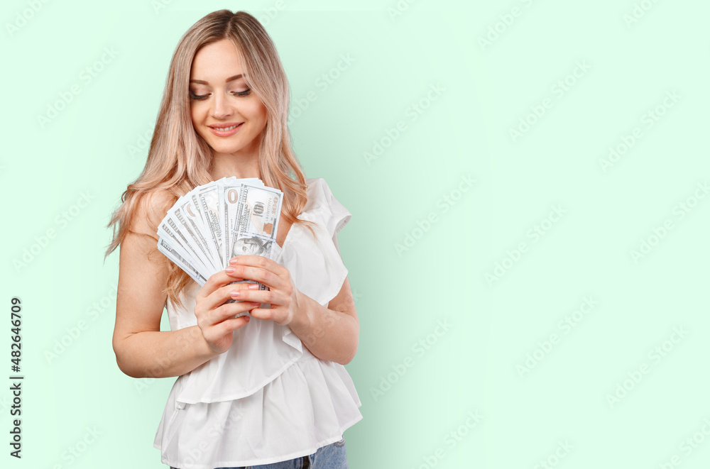 Young happy woman with dollar banknotes in hand isolated on color background Young happy woman with dollar banknotes in hand isolated on color background