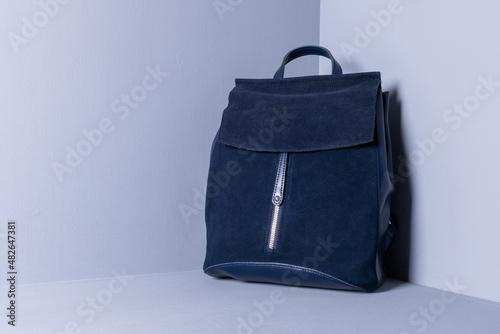 Blue suede backpack on a wooden background painted with gray paint