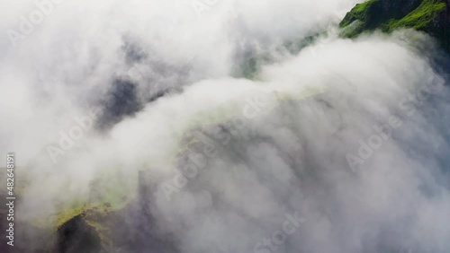 Overhead aerial panorama. Thick white clouds flow above green hills scenery