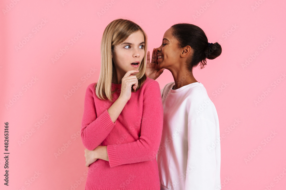Black girl smiling while whispering secret to shocked friend Black girl smiling while whispering secret to shocked friend