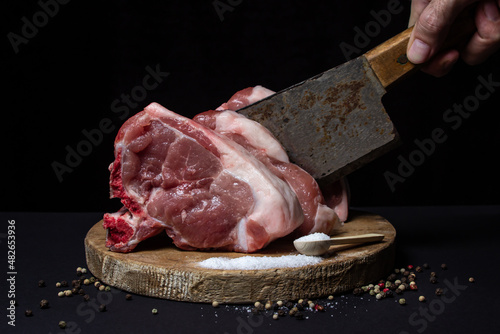 Pork meat on a black background. Meat loin with bone on a wooden board. Meat cooking	