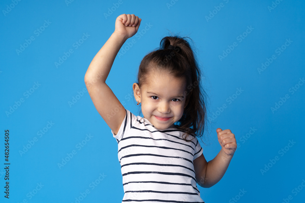 Little cute girl showing her strength on blue background Little cute girl showing her strength on blue background