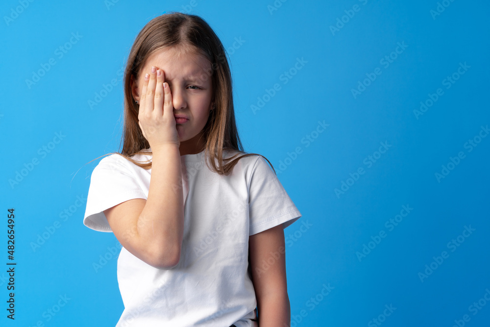 Little girl crying over blue background in studio. Little girl crying over blue background in studio.