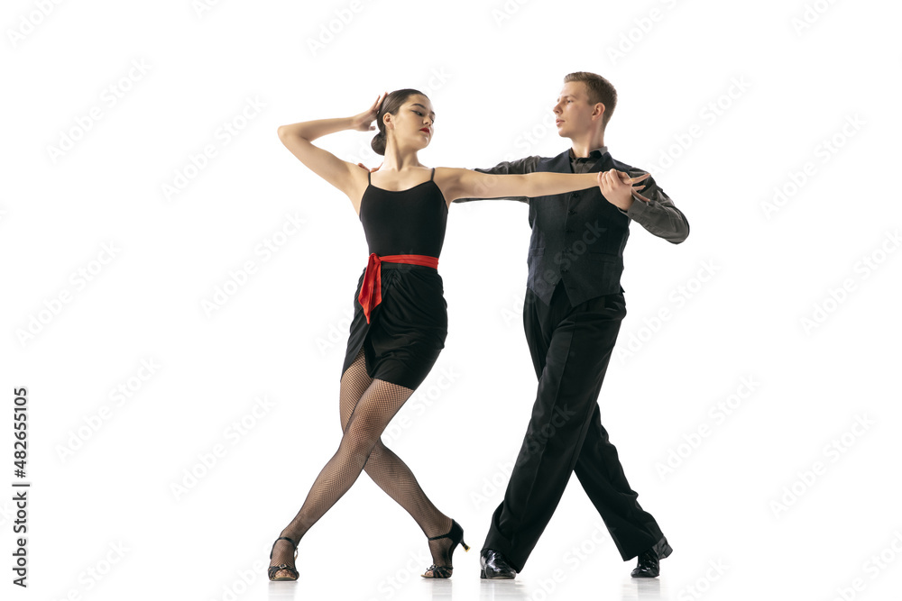 Grace and beautiful dancers, young couple dancing Argentine tango isolated on white studio background. Artists in black stage costumes