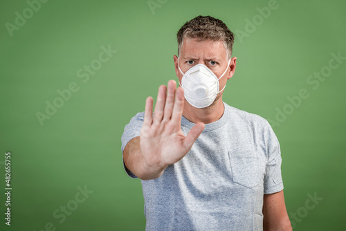 man with ffp2 nose and mouth mask standing in front of green background © epiximages