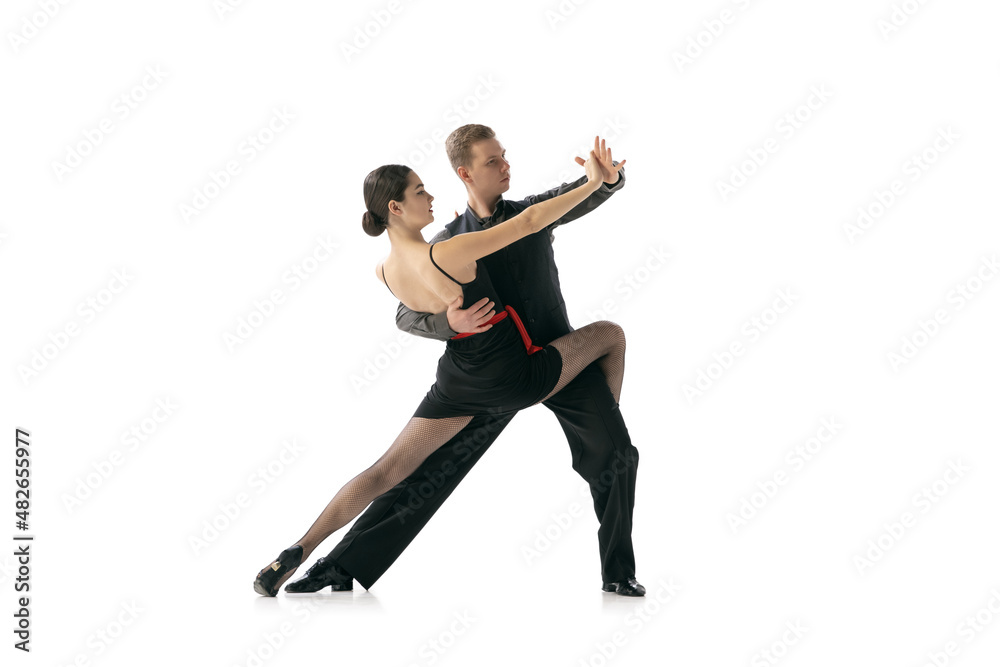 Flexible young couple dancing Argentine tango isolated on white studio background. Artists in black stage costumes