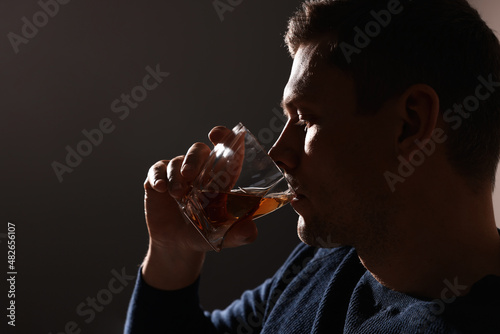 Addicted man drinking alcohol on dark background, closeup