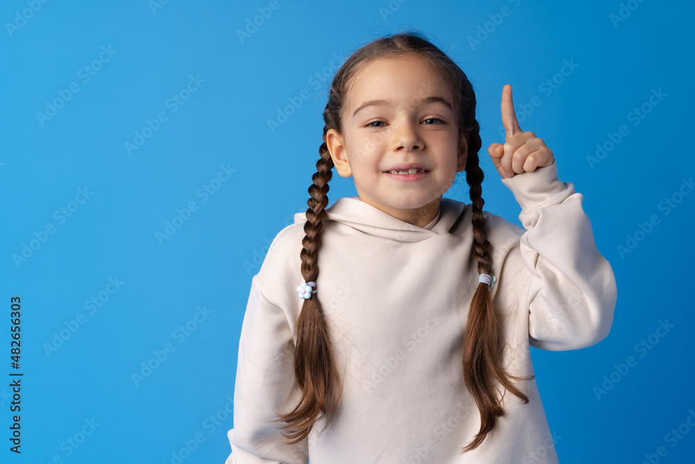 Cute little girl pointing up and having idea against blue background Cute little girl pointing up and having idea against blue background
