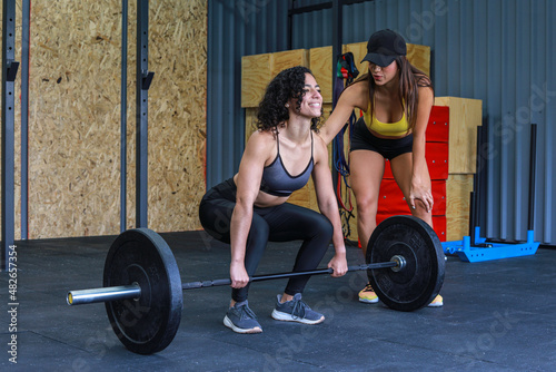 Trainer helping woman to do weights inside a crossfit GYM