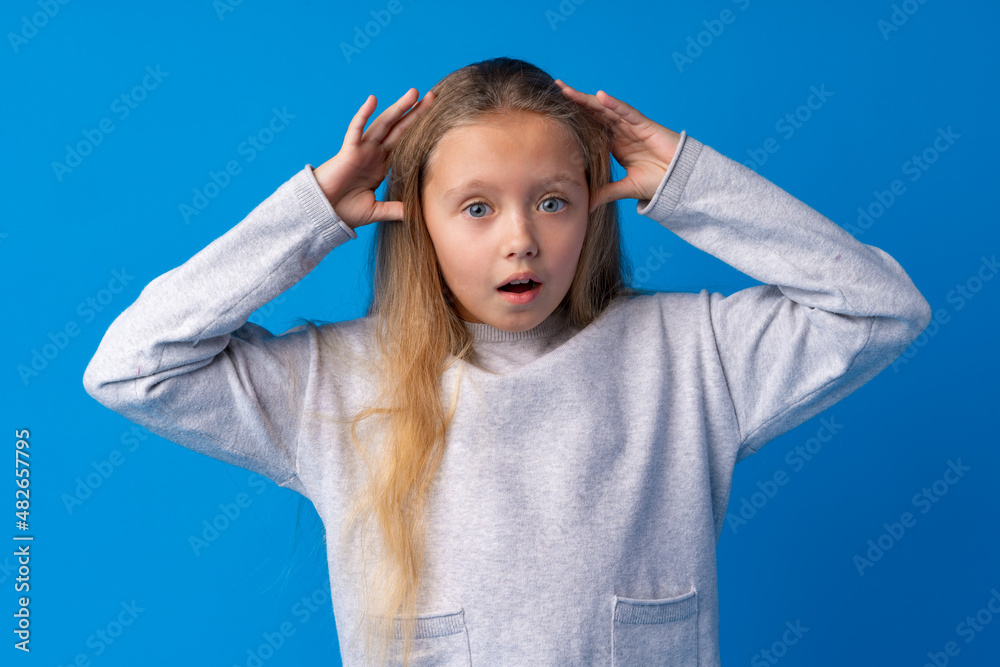 Shocked little girl looking with amazement on blue background Shocked little girl looking with amazement on blue background